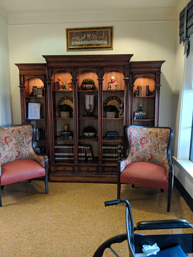 A cozy reading nook featuring elegant upholstered chairs and a wooden display cabinet.