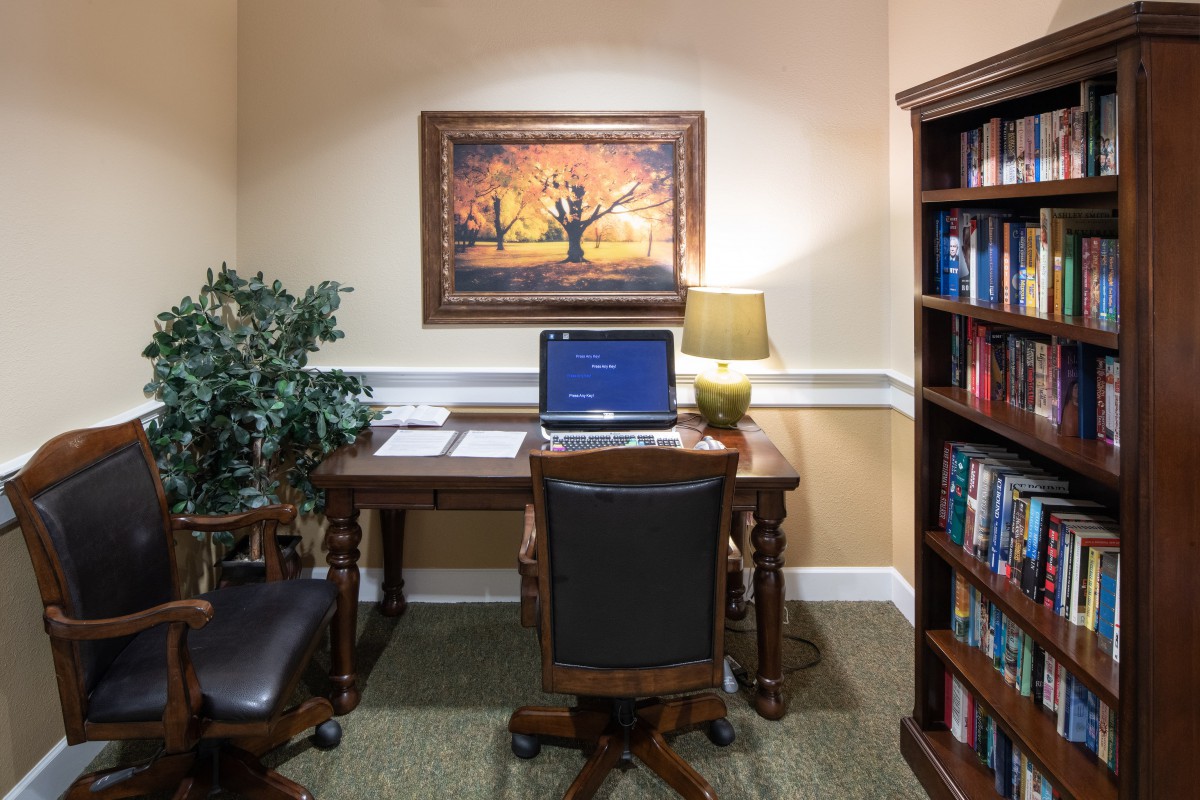 A cozy office space with a desk, laptop, and bookshelf.