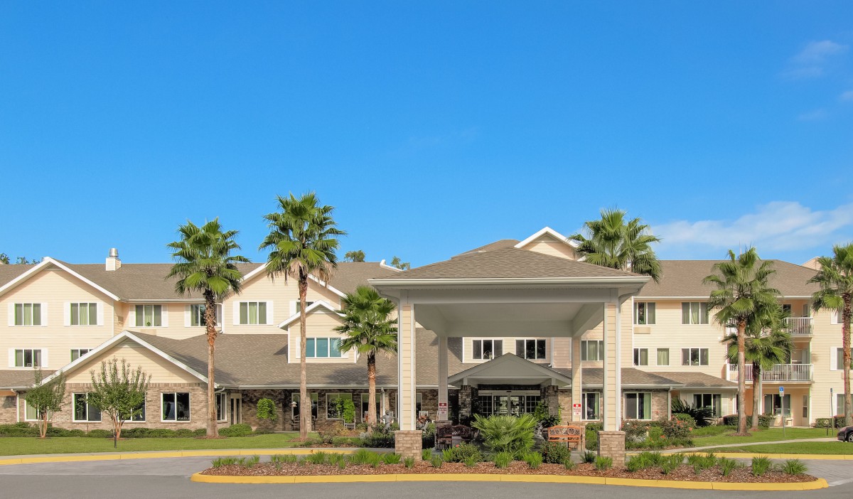 A residential building with palm trees and a grand entrance on a sunny day.