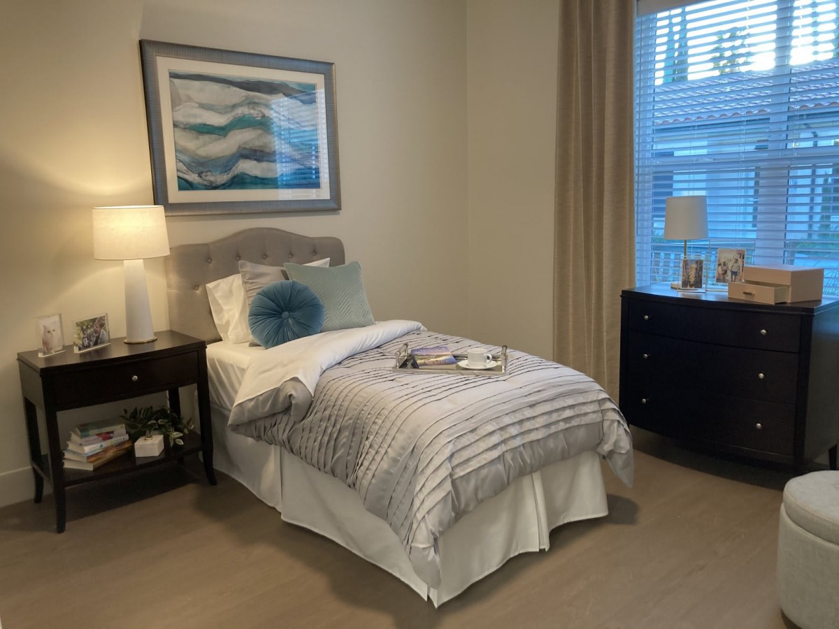 A cozy bedroom with a single bed, nightstand, lamp, and decor.