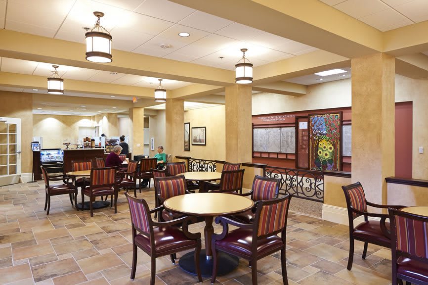 A cozy dining area with tables and chairs, featuring warm lighting.