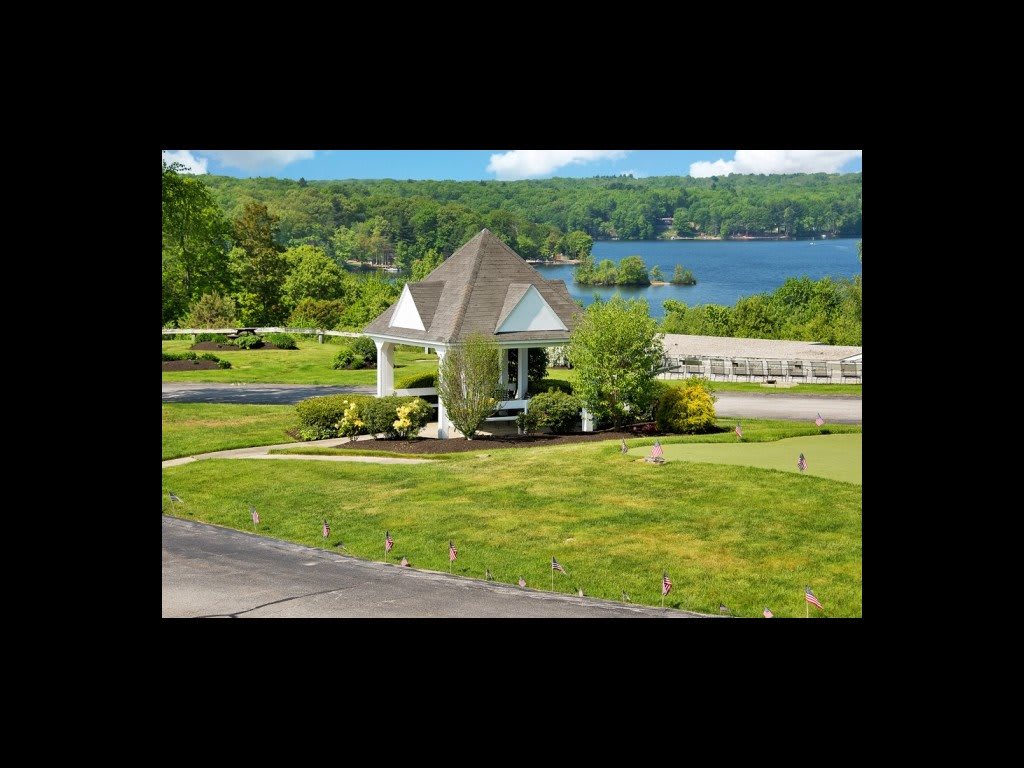 A picturesque gazebo overlooking a serene lake surrounded by lush greenery.