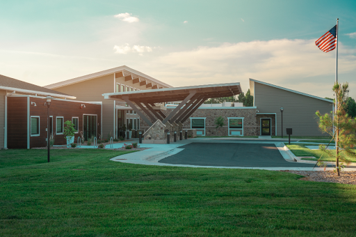 A modern architectural building set in a lush green landscape, basking in the warm glow of sunset.