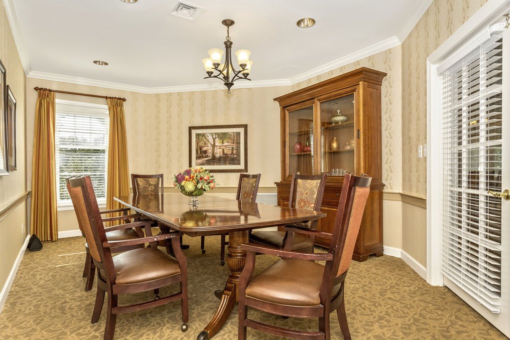 A classic dining room with a wooden table and chairs, illuminated by a chandelier.
