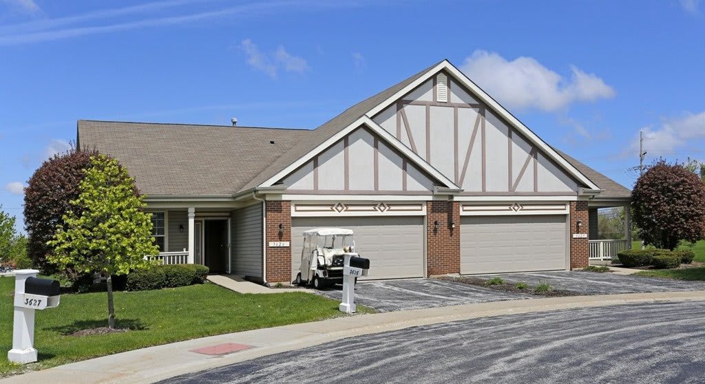 A suburban duplex with garages and a driveway under a clear blue sky.