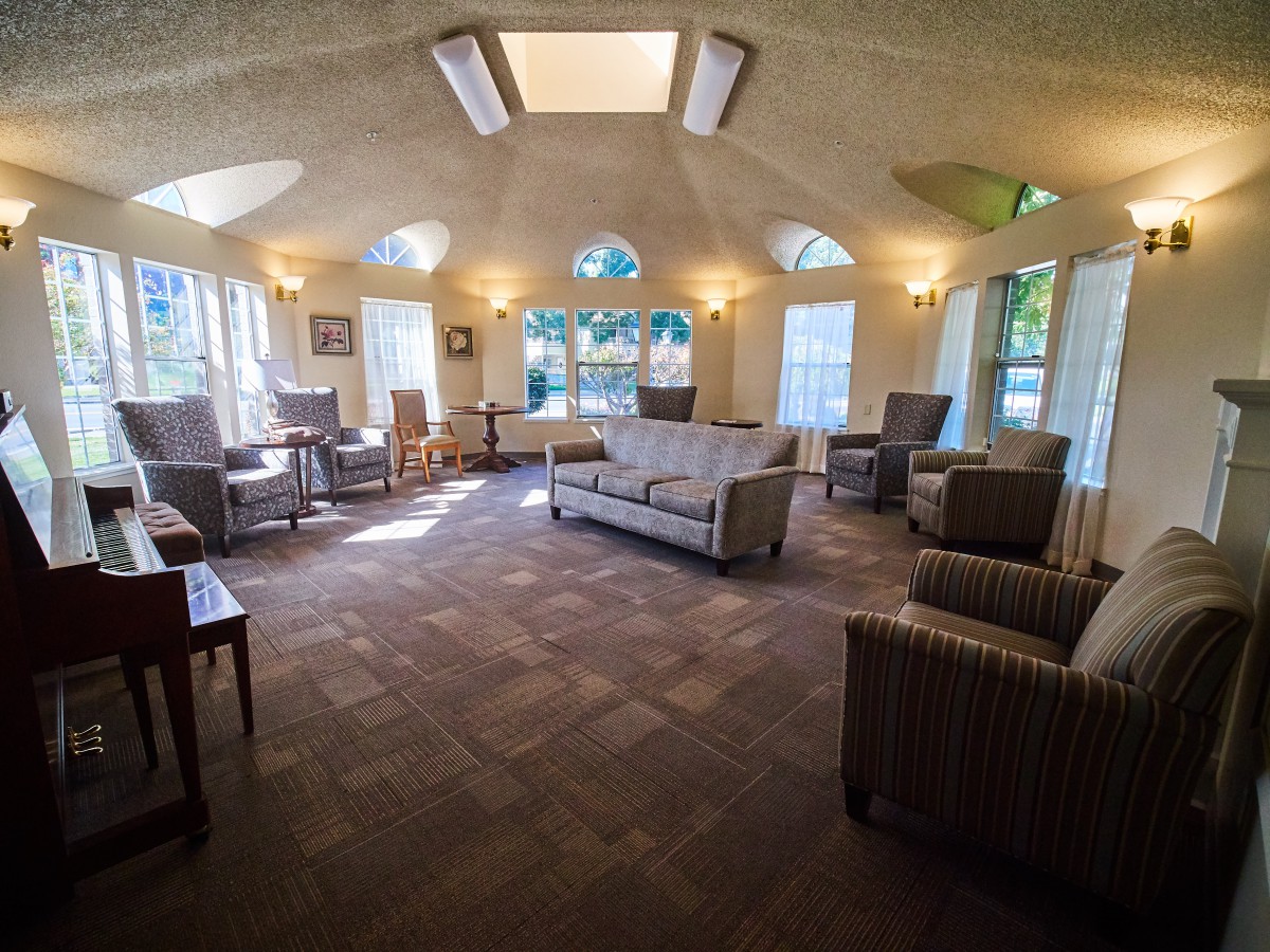 A spacious living room with ample seating, large windows, and natural light streaming in.