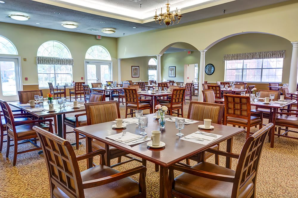 A spacious dining area with neatly arranged tables and chairs, featuring large windows and elegant decor.