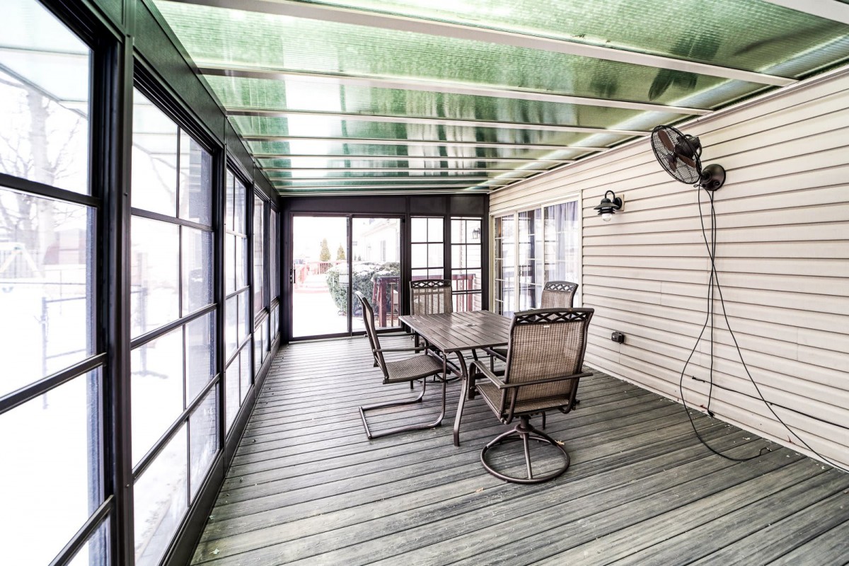 A spacious sunroom with a glass roof, featuring a dining table and chairs for outdoor relaxation.
