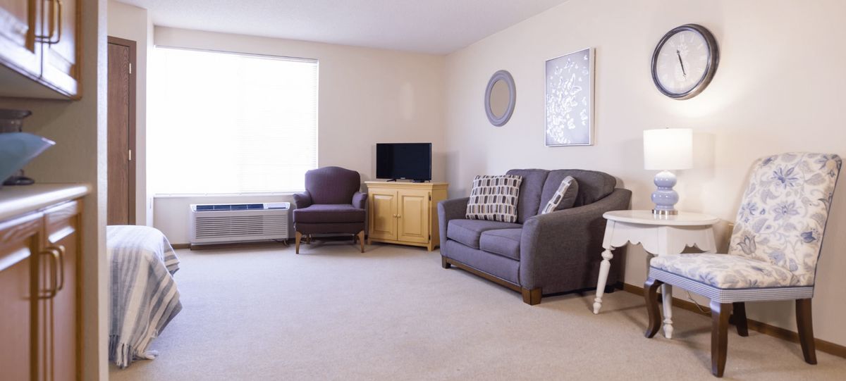 A minimalist living room with a sofa, armchair, and TV.
