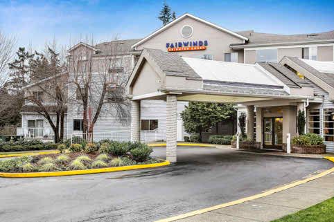 The exterior of a hotel with a covered entrance and landscaped surroundings.
