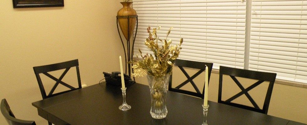 A dining table decorated with a vase of flowers and candles, with a lamp in the background.