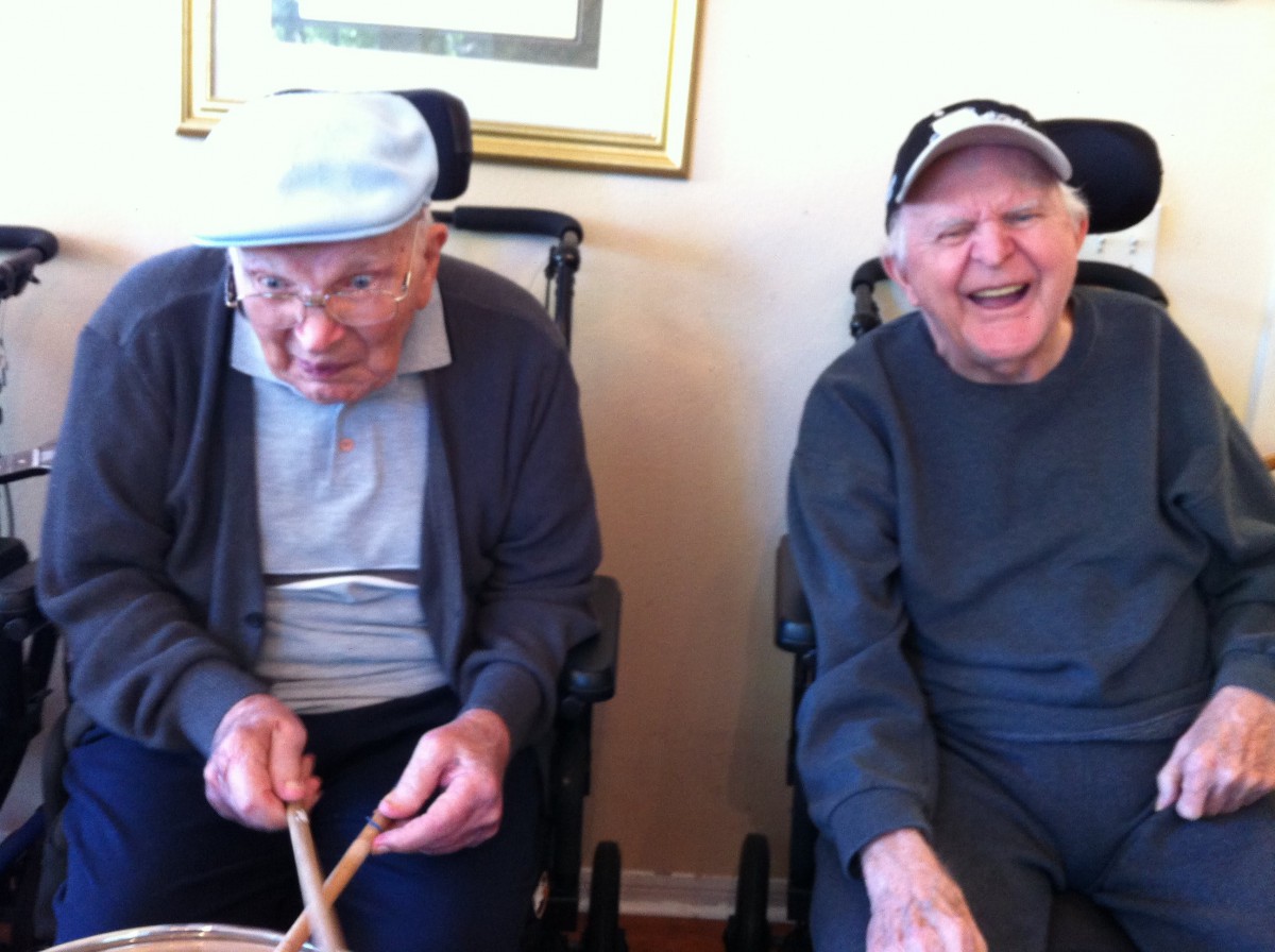 Two elderly men sitting together in wheelchairs, smiling and enjoying their time.