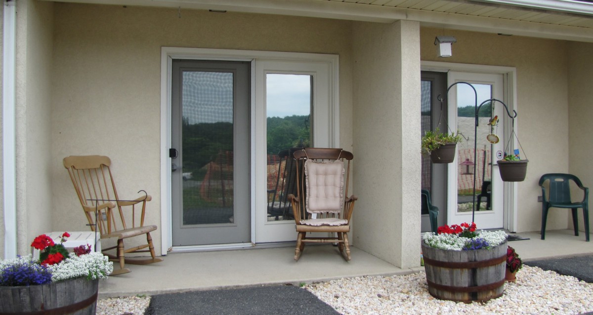 A cozy patio with rocking chairs and decorative plants by the door.