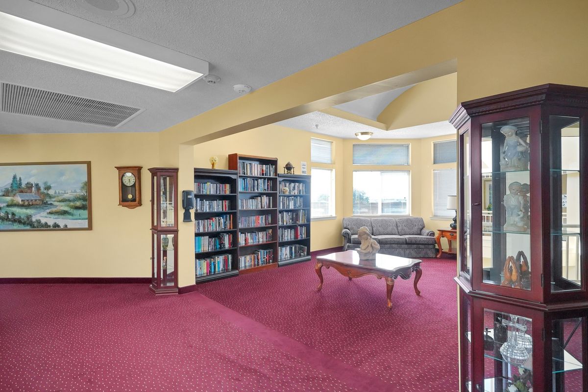 A cozy reading area with bookshelves, a sofa, and a coffee table in a well-lit room.