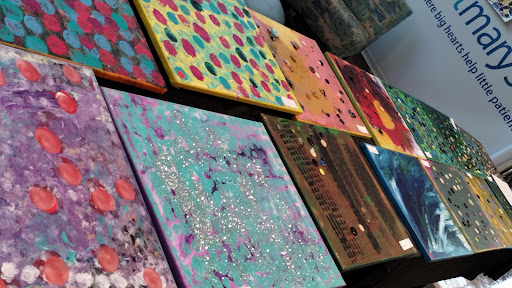 A vibrant display of abstract paintings on canvas, showcasing a variety of colors and patterns.