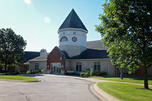 A charming community building with a distinctive tower, surrounded by lush greenery.