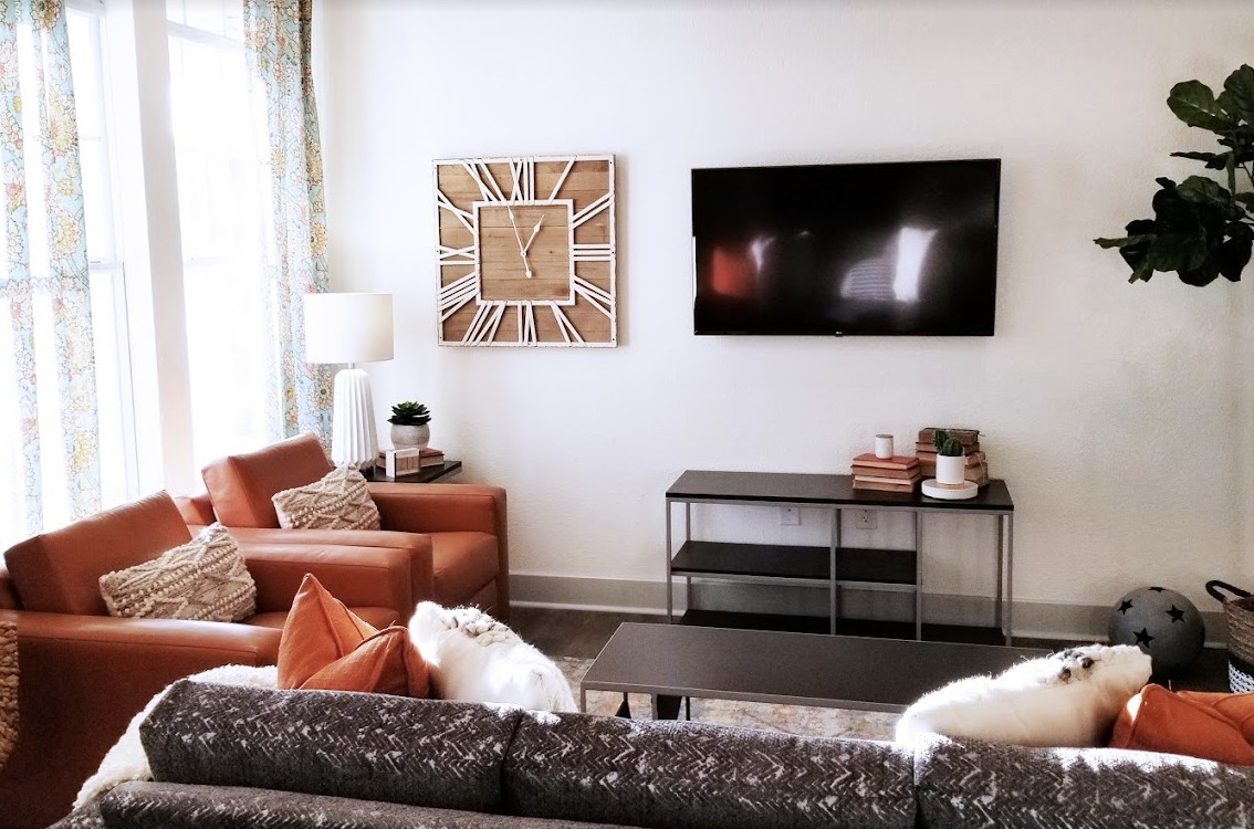A modern living room with stylish decor, featuring a wall-mounted TV, comfortable seating, and contemporary wall art.