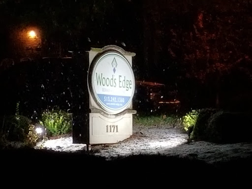 A illuminated sign for Woods Edge, visible in a snowy night setting.