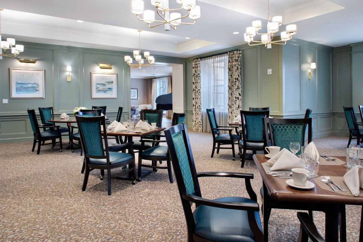 An elegant dining room with neatly arranged tables and chairs under soft lighting.