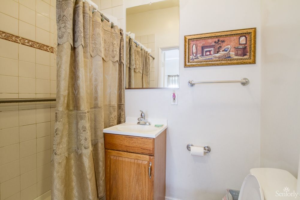 A cozy bathroom with a shower curtain, sink, and decorative wall art.