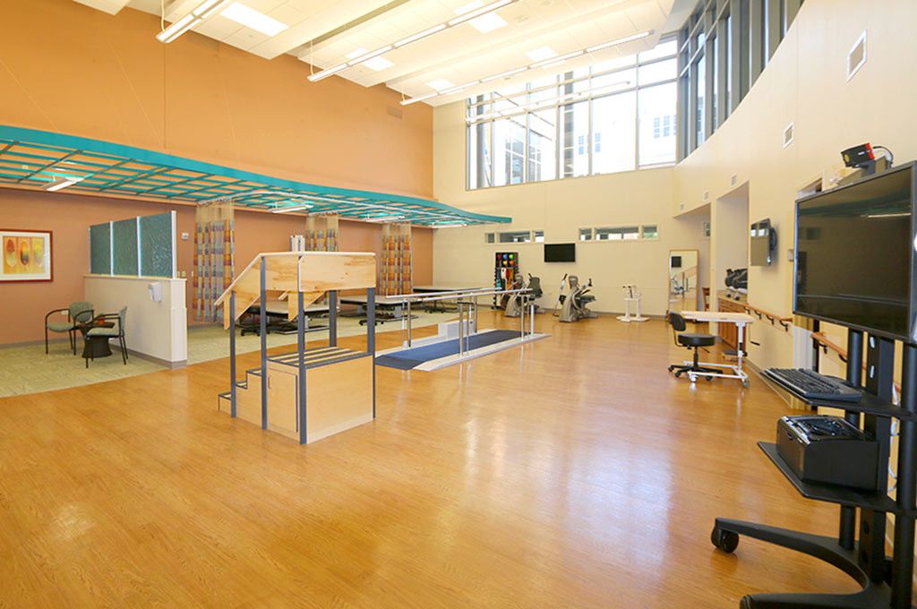 A spacious rehabilitation center equipped with various physical therapy tools and exercise equipment.
