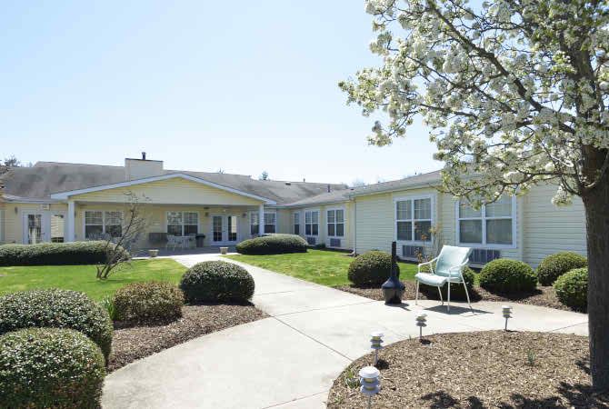 A sunny view of a residential building with a landscaped garden and pathway.