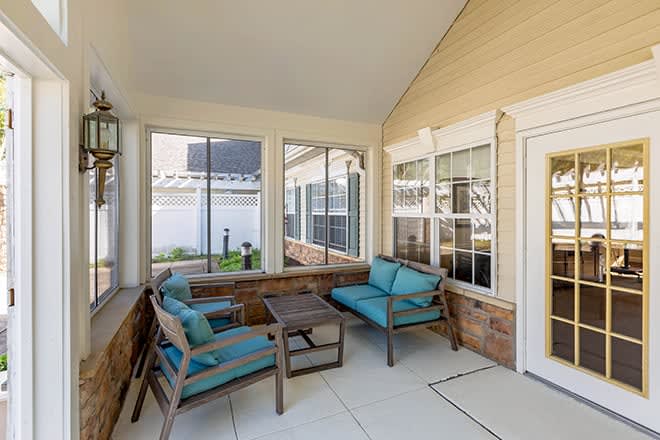 A cozy patio area with cushioned seating and large windows.