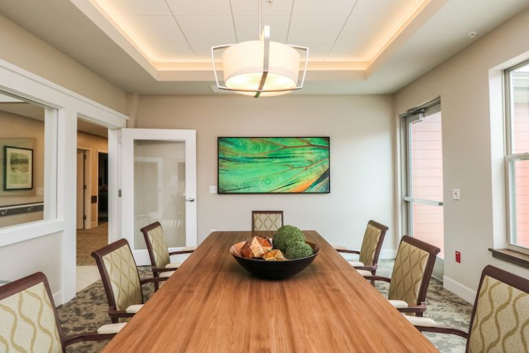 A modern dining room featuring a large wooden table, stylish chairs, and contemporary artwork.