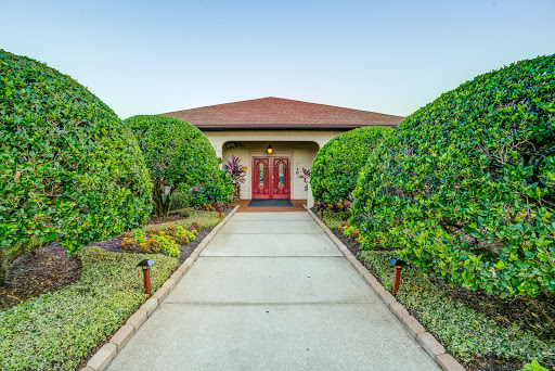 A beautifully landscaped entrance to a home, featuring well-manicured bushes and a welcoming pathway.