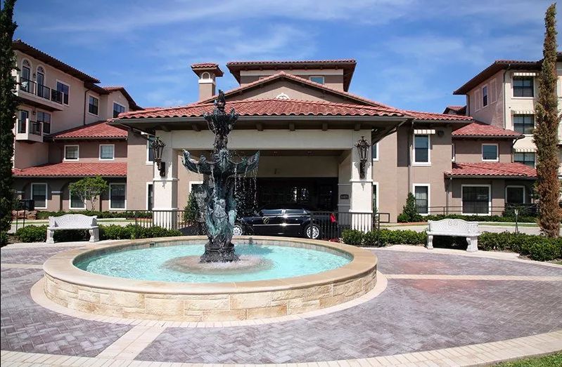 A view of a building with a fountain in the foreground on a sunny day.