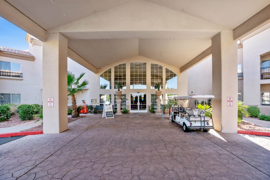 A covered building entrance with a golf cart parked nearby.