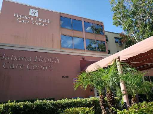 Exterior view of a healthcare facility with palm trees in the foreground.