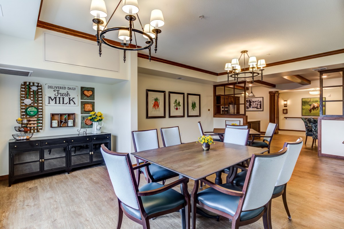 A stylish dining room featuring a large table, elegant chandeliers, and decorative wall art.