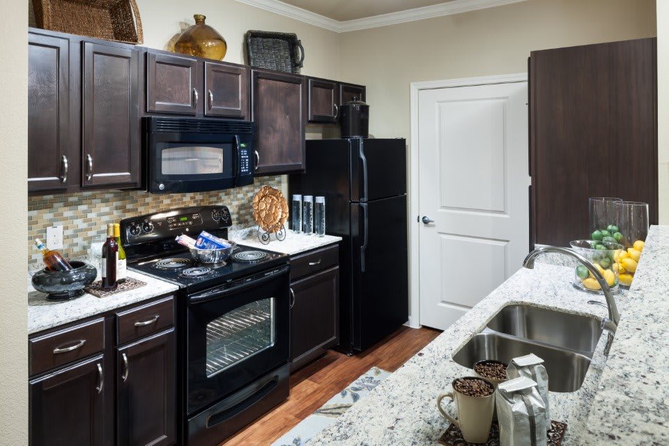 A modern kitchen with dark cabinets and various appliances.