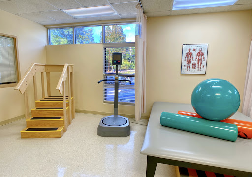 A well-equipped physical therapy room featuring exercise equipment, a staircase for rehabilitation exercises, and an exercise ball.