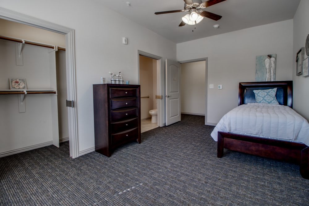 A spacious bedroom with a bed, dresser, and ceiling fan.