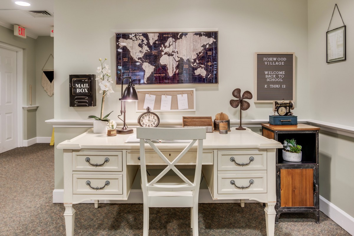 A vintage-inspired home office setup featuring a white desk with drawers, a world map on the wall, and carefully arranged decor items.