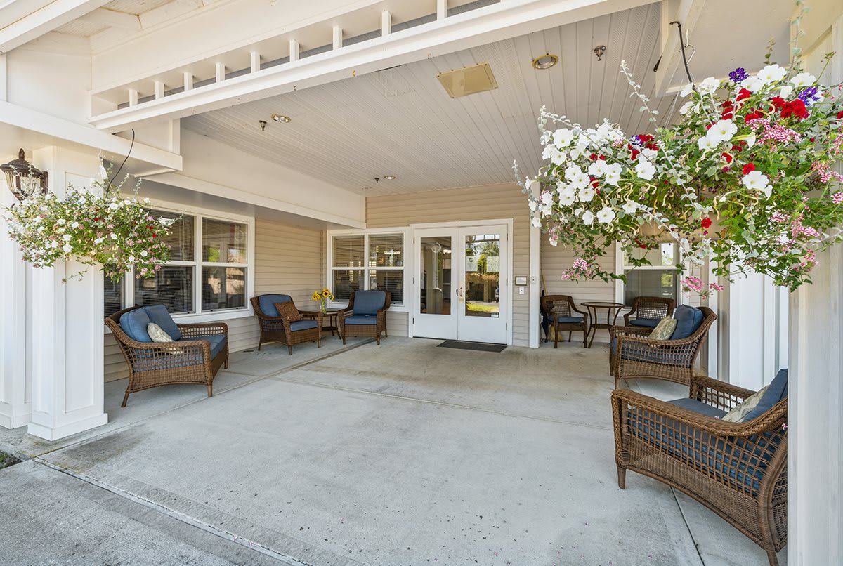 A welcoming patio area with wicker furniture and flower arrangements at the entrance.