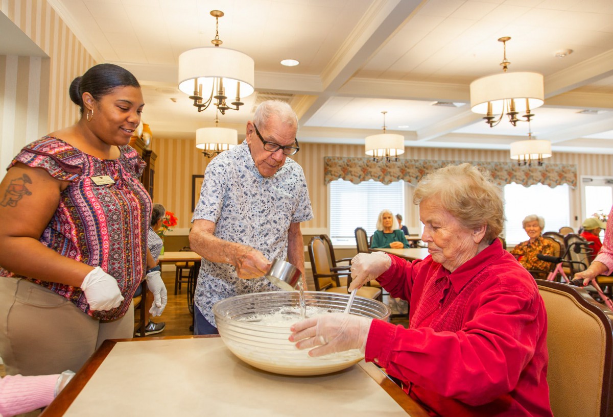 A group of people engaging in a communal cooking activity indoors.