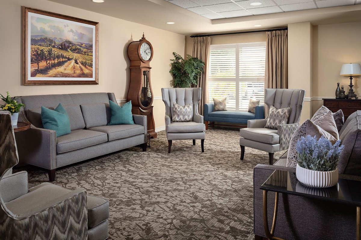 A cozy living room with elegant furniture, featuring a sofa and armchairs, accented by a classic grandfather clock.