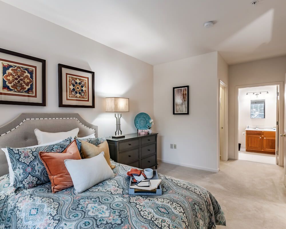 A cozy bedroom with patterned bedding, decorative pillows, and wall art creating a welcoming atmosphere.