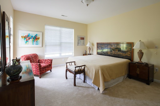 A cozy and well-lit bedroom featuring a large bed, comfortable seating, and artistic decor.