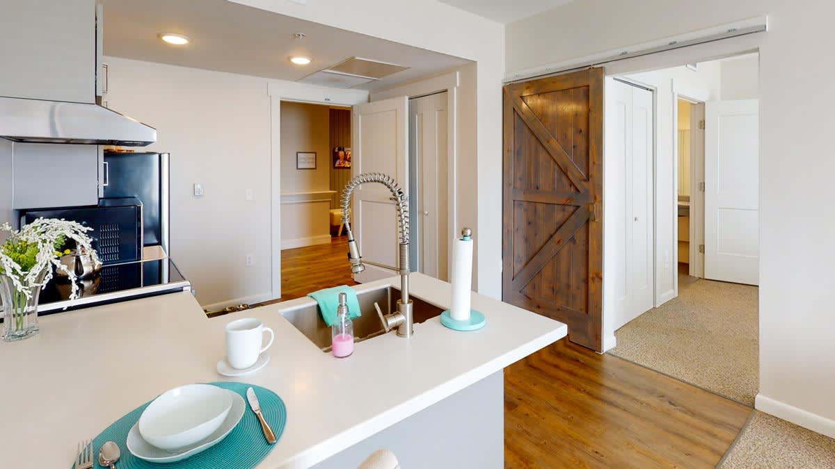 A modern kitchen with a sleek countertop, featuring a dining area and a stylish barn door.