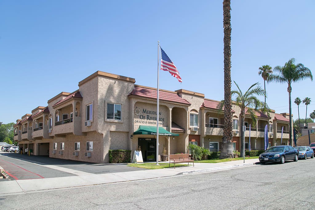 A two-story building with an American flag and palm trees in a sunny setting.