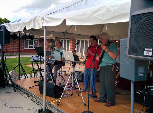 A lively outdoor performance by a band under a tent.
