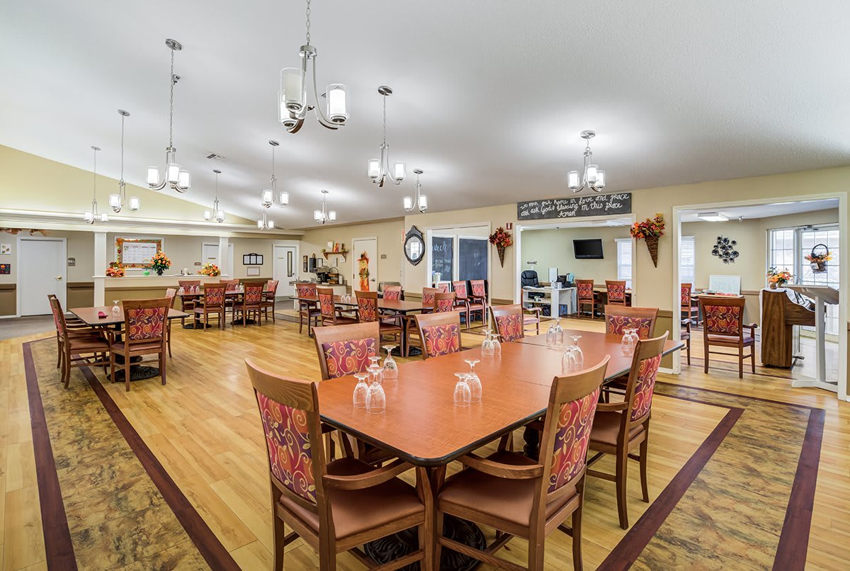 A spacious dining area with neatly arranged tables and chairs, featuring elegant lighting fixtures.