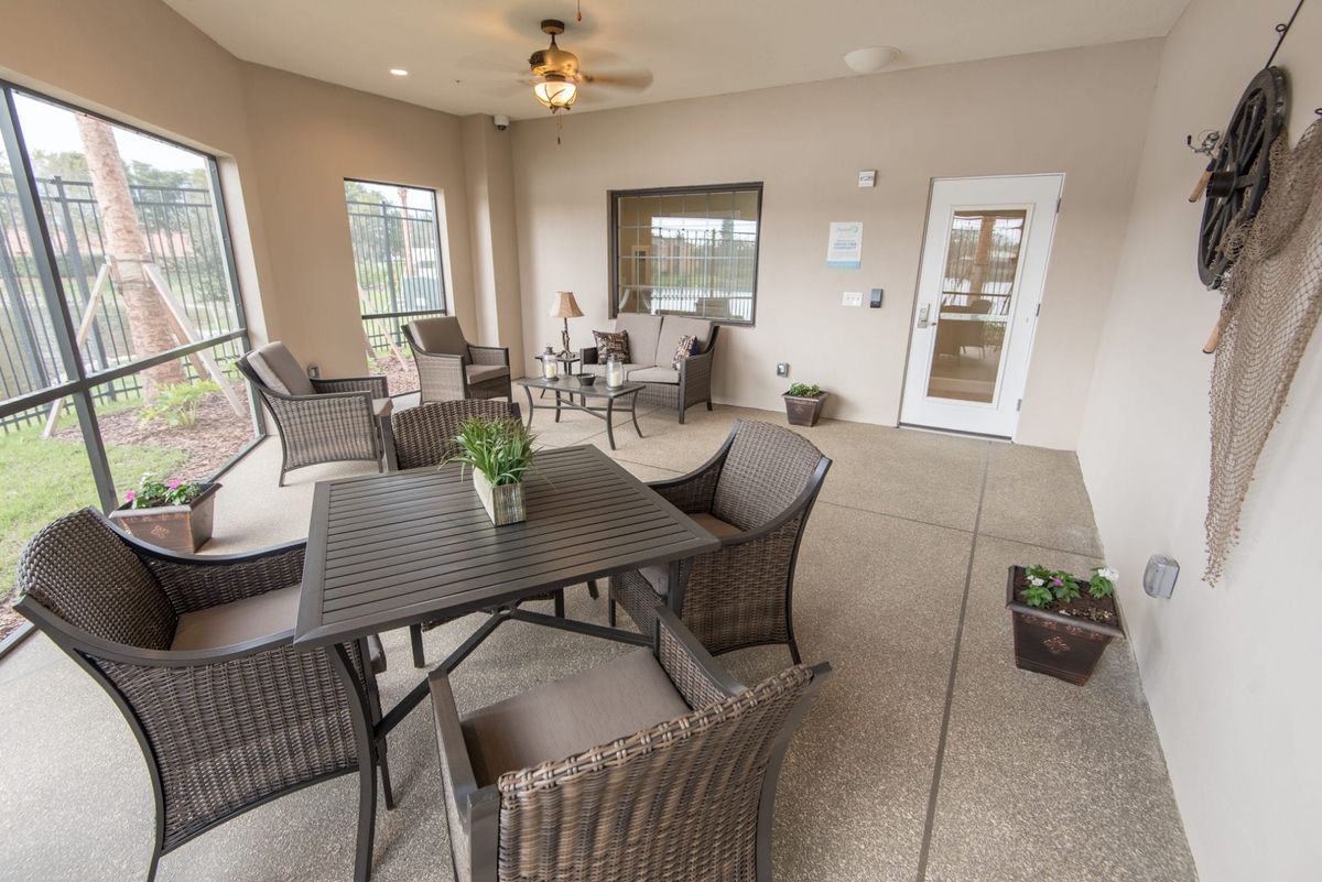 An inviting indoor-outdoor patio area with comfortable seating and a ceiling fan.