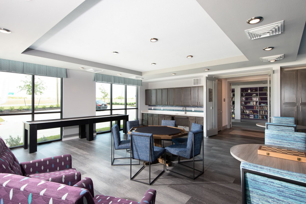 A modern and spacious living area with large windows, equipped with stylish furniture including tables and chairs.