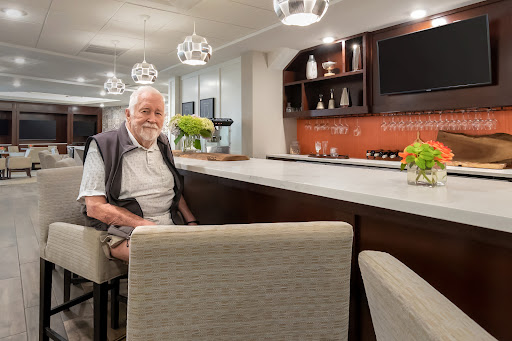 An elderly man enjoying a moment at a stylish bar setting, surrounded by modern decor.