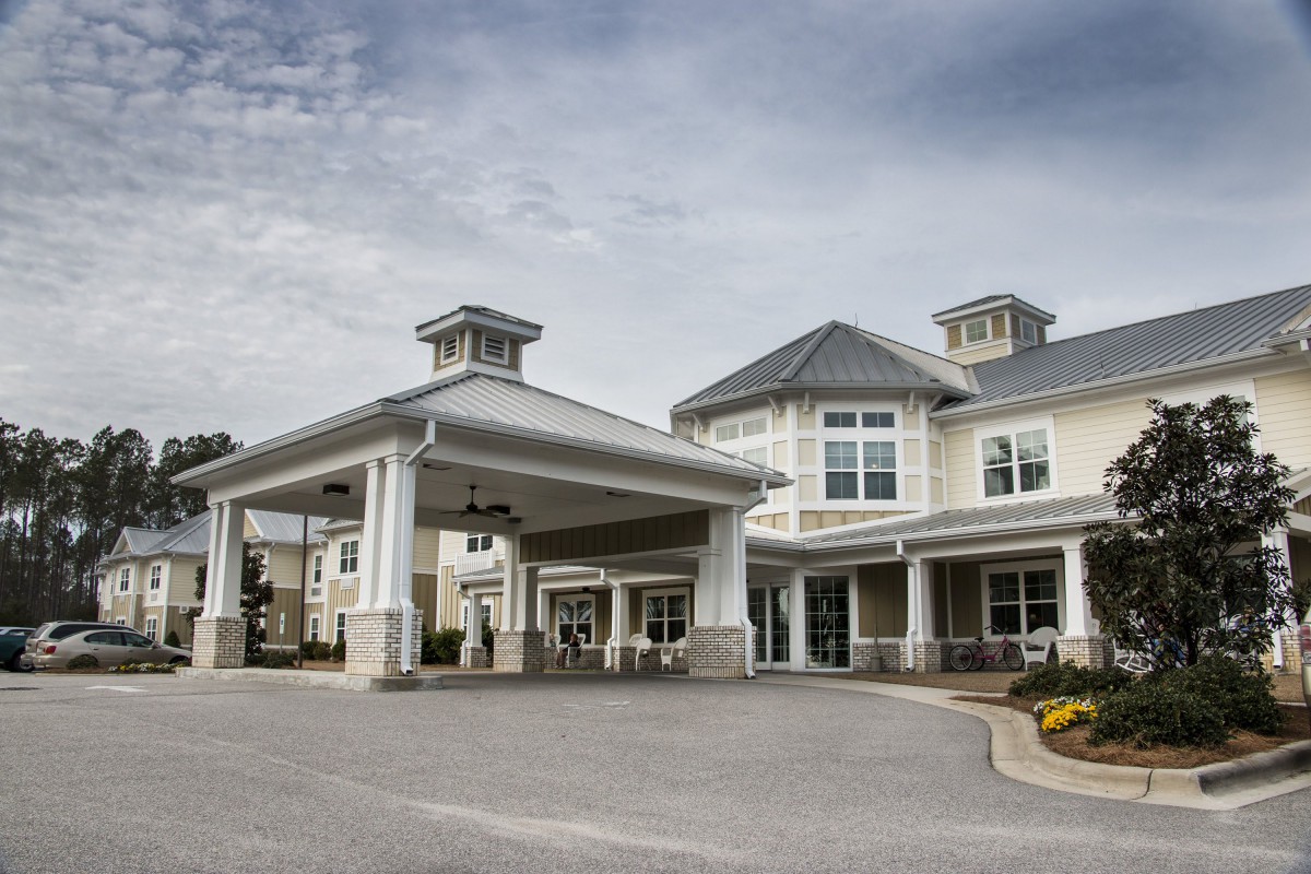 A large residential building with a covered entrance and driveway.